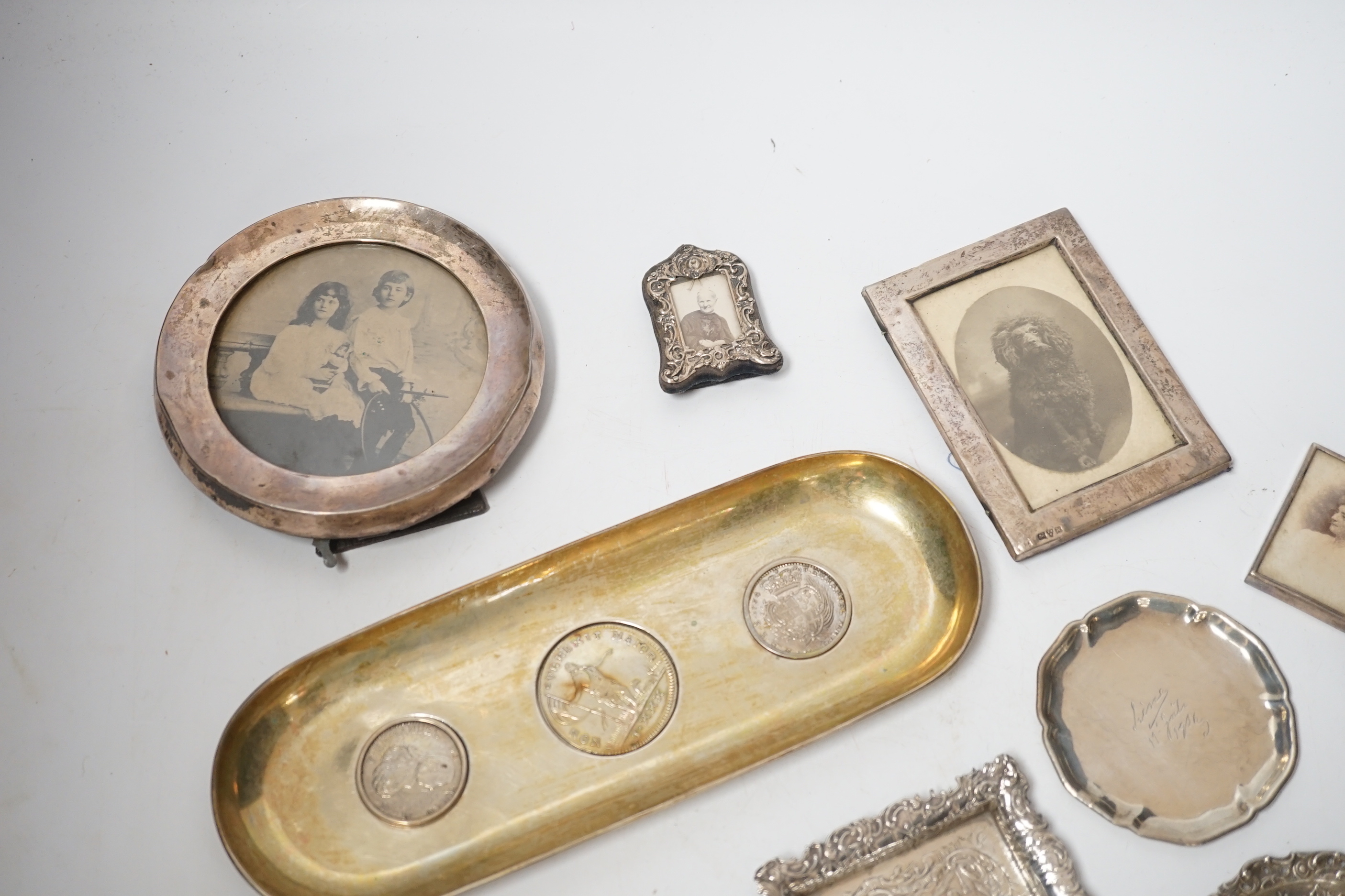 Sundry small silver and white metal items including seven photograph frames, largest 12.5cm, an 800 standard oval dish, inset with three coins, five small dishes and a timepiece.